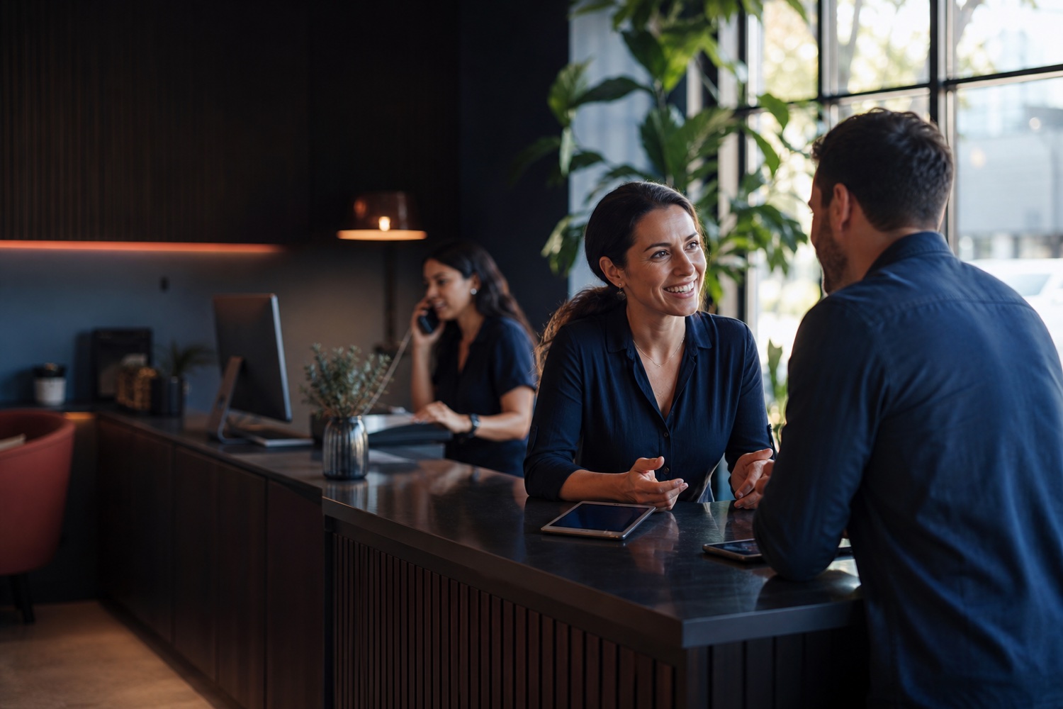 A hospitality professional listening to a guest while a colleague answers an inquiry
